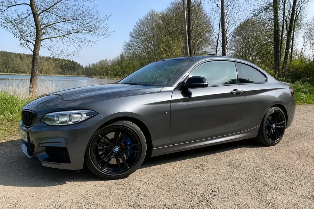 Voiture grise BMW avec jantes noires dans un environnement naturel paisible