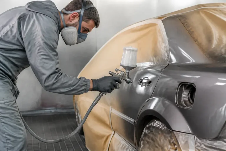 Technicien appliquant peinture automobile dans atelier spécialisé en cap carrosserie peinture