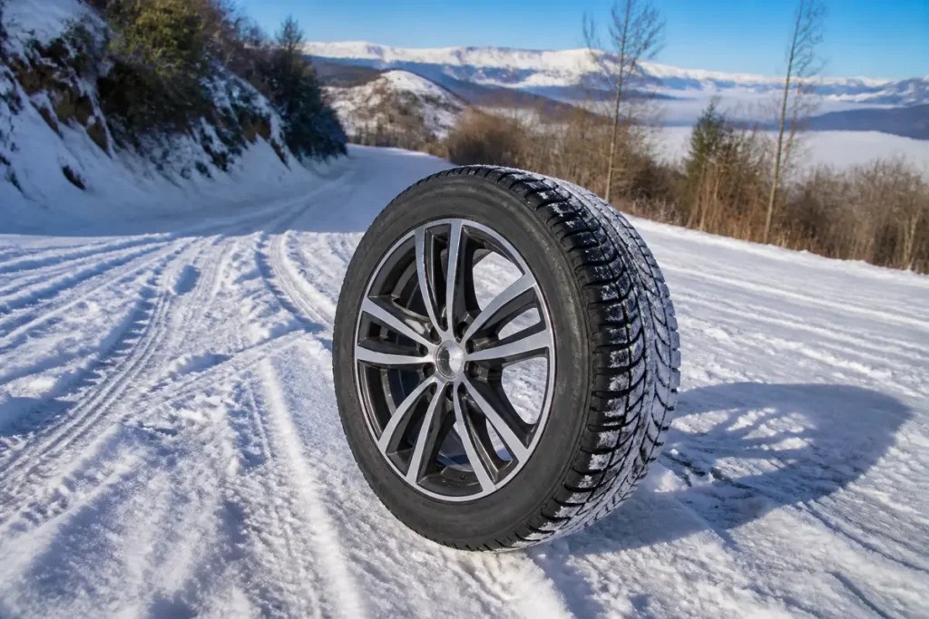 Jante hiver sur route enneigée en montagne avec ciel bleu et arbres en arrière-plan