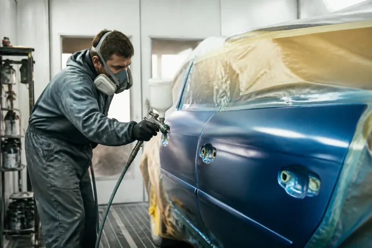 Carrossier appliquant une peinture bleue sur portière, évoquant le salaire en peinture automobile