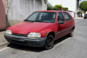 Voiture d'occasion rouge avec défauts visibles, illustrant un vice caché dans une voiture.
