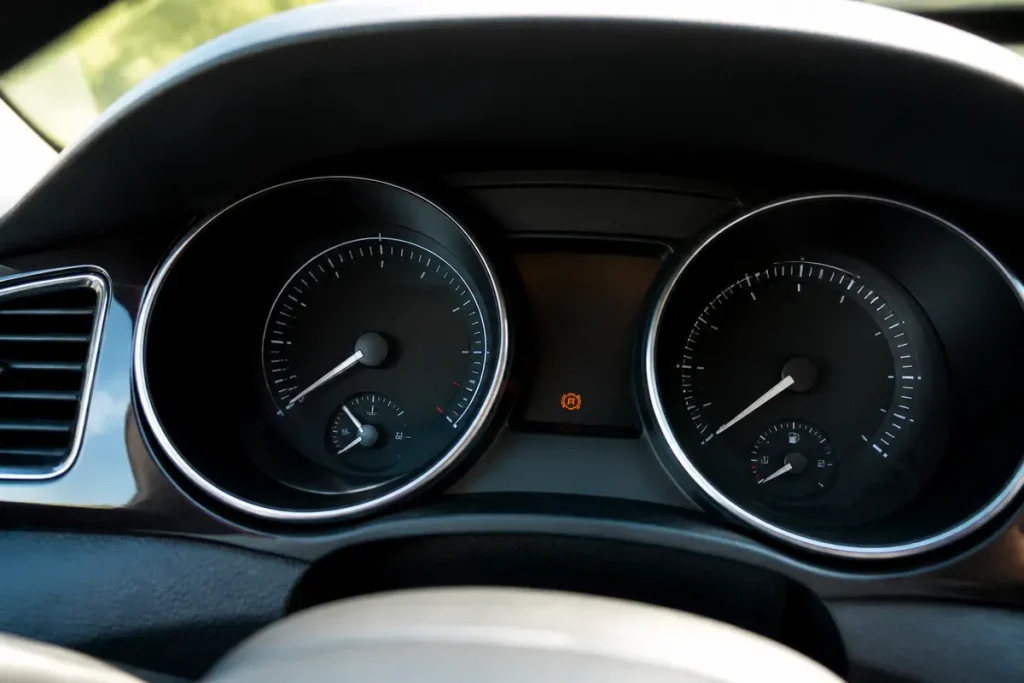 Tableau de bord de voiture avec voyant orange rond représentant une voiture dedans allumé