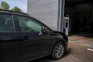 Voiture noire attend contrôle technique dépassé mais prévue avec rendez-vous près d’un garage.