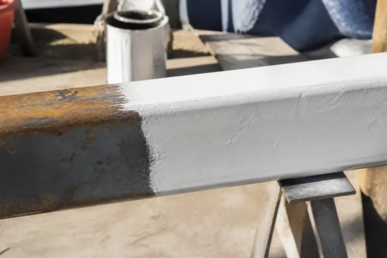 Poutre en métal partiellement recouverte de peinture antirouille blanche sur tréteau en extérieur